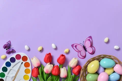 Easter background with painted eggs, colors and tulips and butterflies. Stock Photos