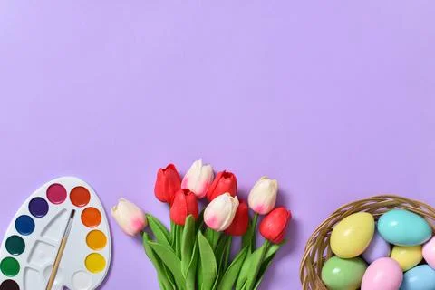 Easter background with painted eggs, paints and tulips. Copy space. Stock Photos