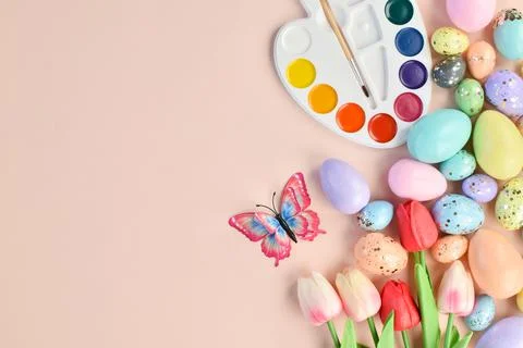 Easter background with painted eggs, tulips, paints and butterflies on beige. Foto stock