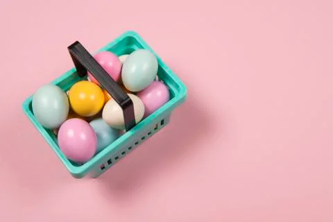 Easter background with pastel colored easter eggs in a shopping basket on a p Stock Photos