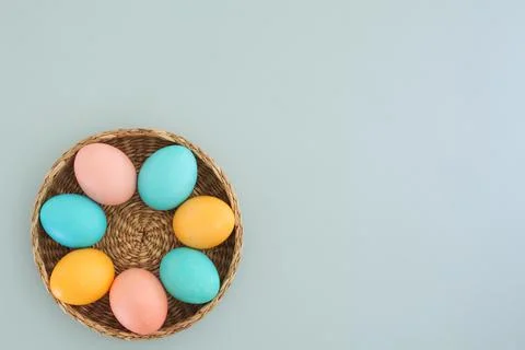 Easter background with place for text. Pastel Easter eggs in a basket on a blue Stock Photos