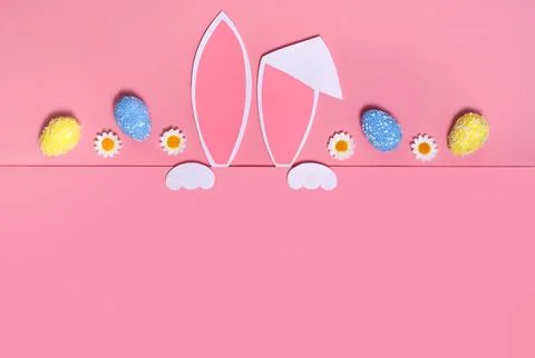 Easter background. Rabbit ears and Easter eggs on a pink background.Copy space Stock Photos