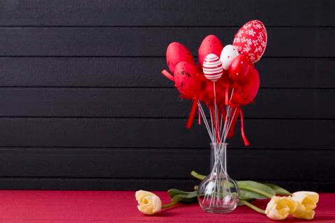 Easter background with red and white eggs and yellow tulips Stock Photos