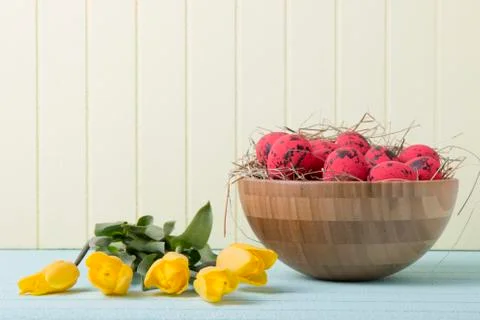 Easter background with red eggs and yellow tulips on yellow wall Stock Photos