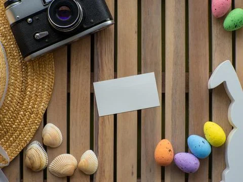 Easter background with straw hat, photo camera, colorful eggs and white rabbit Stock Photos