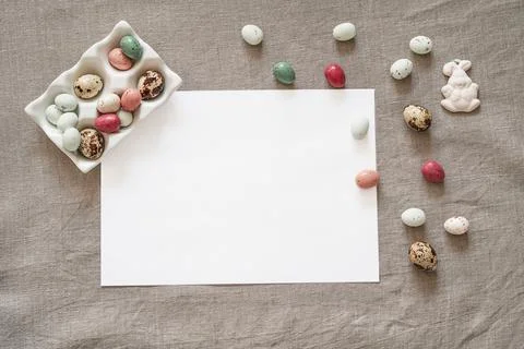 Easter background with white paper blank and colored easter eggs. Stock Photos