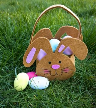 Easter, a bag in the shape of a hare with eggs stands on green grass Stock Photos