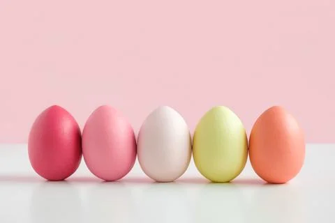 Easter banner with colorful Easter Egg in a row on white table and pink backg Stock Photos