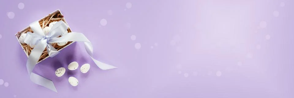 Easter banner with Easter eggs in a gift box with lavender blush ribbons on pale Stock Photos