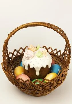 Easter basket with colored Easter eggs and sweet paska on a white background. 库存照片