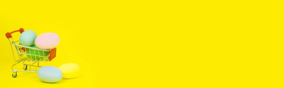 Easter . Basket with Easter eggs on a yellow background. With place for text. Stock Photos