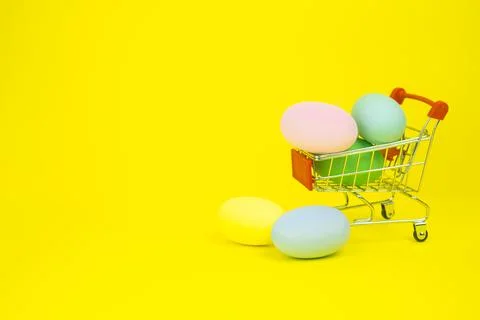 Easter . Basket with Easter eggs on a yellow background. With place for text. Stock Photos