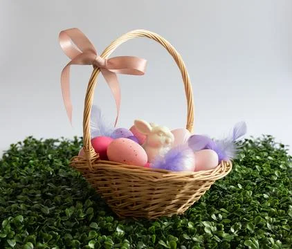 Easter basket with eggs, rabbit and feathers on white background. Stock Photos