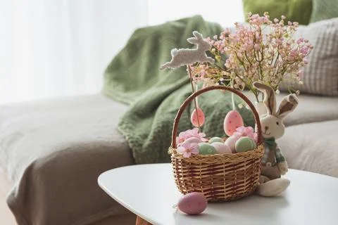 Easter Basket with Ester Eggs,  Plush Bunny and Spring Decor on White Table.. Stock Photos