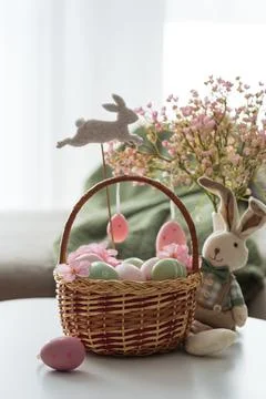 Easter Basket with Ester Eggs,  Plush Bunny and Spring Decor on White Table.. Stock Photos
