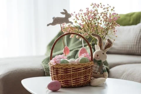 Easter Basket with Ester Eggs,  Plush Bunny and Spring Decor on White Table.. Stock Photos