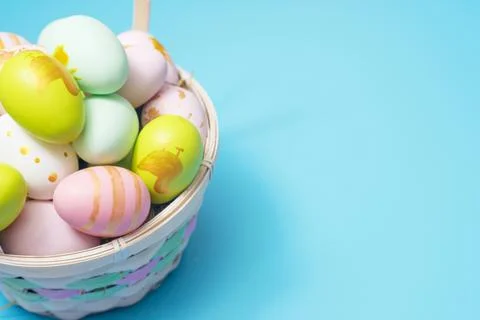 Easter basket filled with painted Easter Eggs over a blue background. Colorfu Stock Photos