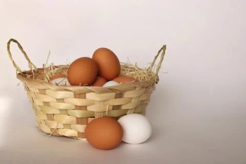 Easter basket, next to it are two chicken eggs. Close-up. A wicker basket fil Stock Photos