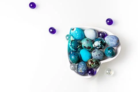 Easter blue quail eggs in a plate in the shape of a heart on a white table Stock Photos