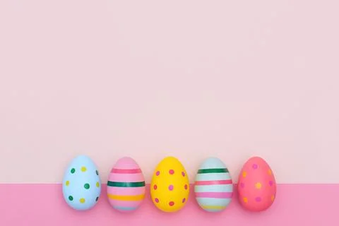 Easter border of bright Easter eggs on a pink background. Stock Photos