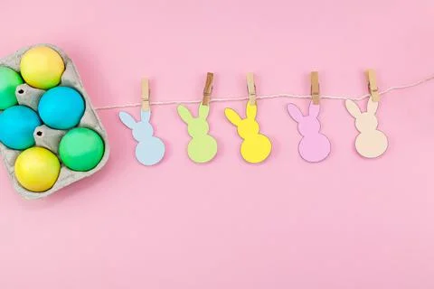 Easter. Box of colorful eggsand easter decoration of the room on a pink backg Stock Photos