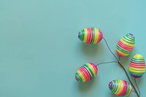 Easter branch of multicolored rainbow eggs on blue background Stock Photos
