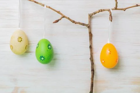 Easter branches with Easter eggs hanging on white painted vintage wood backgr Stock Photos