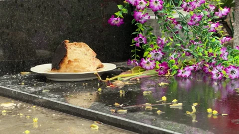 Easter Bread And Artificial Flowers Sit On A Wet Granite Tomb In A Cemetery Stock Footage 335153161