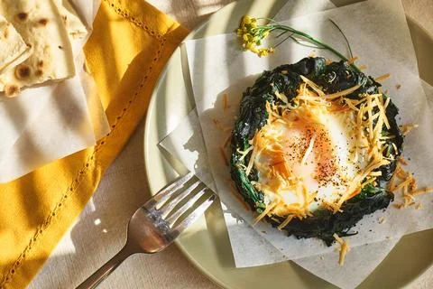 Easter breakfast idea. Baked spinach egg nests decorated with grated cheese.. Stock Photos