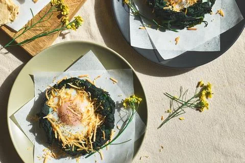 Easter breakfast idea. Baked spinach egg nests decorated with grated cheese.. Stock Photos