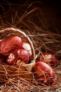 Easter brown egg with a pattern of grasses, dyed in onion skins in a wicker b Stock Photos