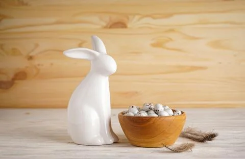 Easter bunny and Easter eggs in a bowl on a wooden background. Space for text Stock Photos