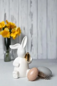 Easter bunny and eggs on table, bouquet of daffodils on background. Copy space Stock Photos