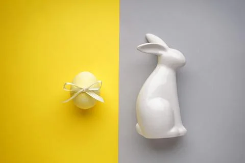 Easter bunny ceramic with yellow easter egg with ribbon on a yellow-grey back Stock Photos