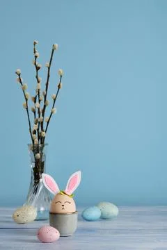 Easter bunny eggs in egg holder on blue background. Multicolored eggs and spr Stock Photos