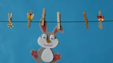 The Easter bunny is hanging on the clothesline on blue background. Stock Footage 88000461