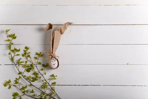 Easter bunny made from egg and paper ears with green branch on wooden boards Stock Photos