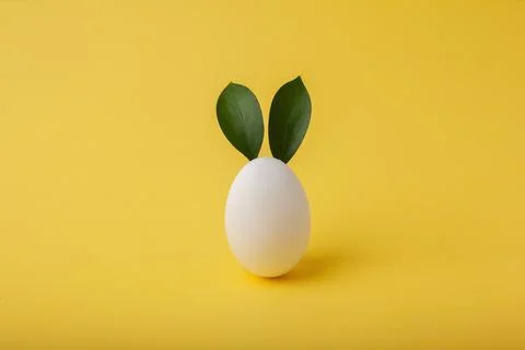 .Easter bunny made from eggs and green leaves on a yellow background. Minimal Stock Photos