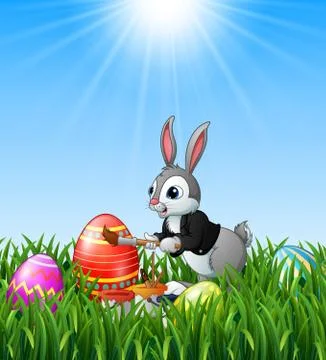 Easter bunny painting easter eggs in the grass background Stock Illustration