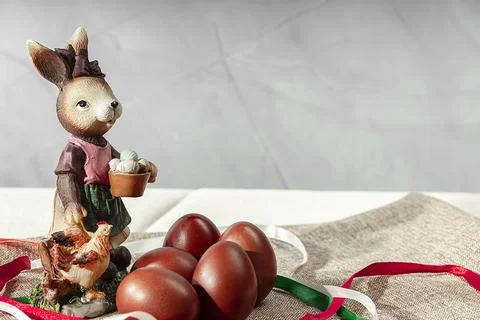 Easter Bunny sits among multi-colored eggs on a light background. Easter back Stock Photos