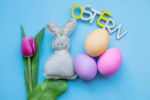 Easter bunny, tulip, easter eggs and the inscription easter in german on a blue Stock Photos
