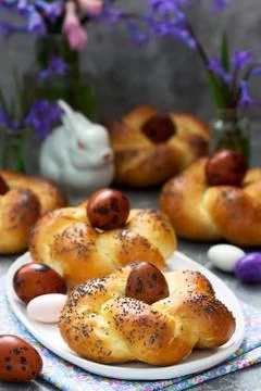 Easter buns, colored eggs and flowers on a gray concrete background. Stock Photos