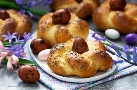 Easter buns, colored eggs and flowers on a gray concrete background. Stock Photos