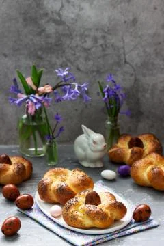 Easter buns, colored eggs and flowers on a gray concrete background. Stock Photos