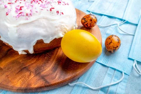 Easter cake and colored eggs are on blue medical masks. Flat lay. Copy space. Stock Photos