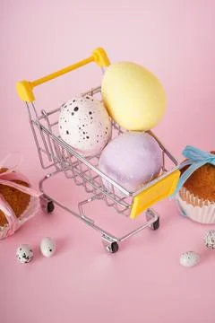 Easter cake and Easter eggs in a cart with flowers on a pink background. Happ Stock Photos
