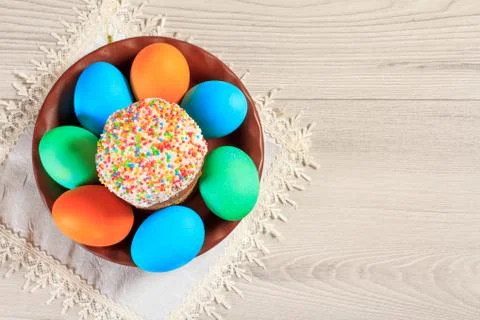 Easter cake and painted eggs on a plate with wooden background. Stock Photos