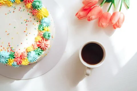 Easter cake decorated with multi-colored cream next to tulips and coffee Stock Photos