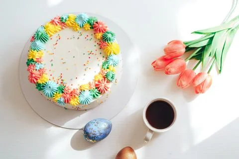 Easter cake decorated with multi-colored cream next to tulips and eggs Stock Photos