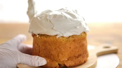 Easter cake decoration.Hands in gloves apply white icing to a fresh Easter cake Stock Footage 300566249